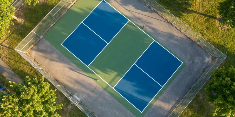 wide top view of an empty blue and green pickleball court with crisp white lines