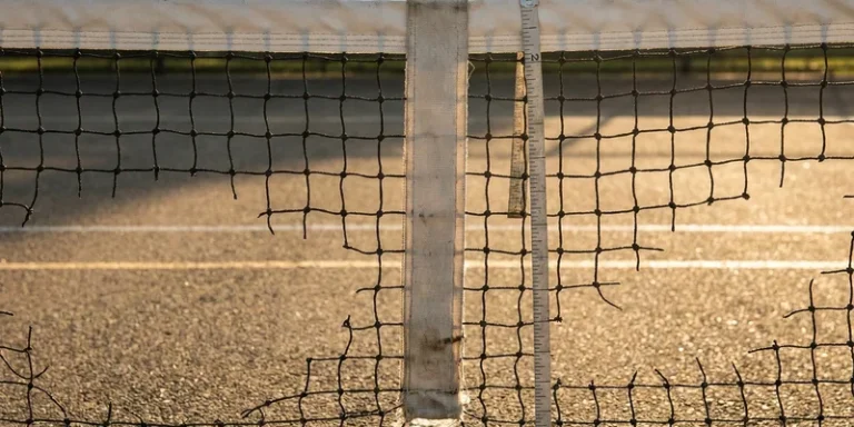 close-up of the center of a pickleball net with a measuring tape hanging from the top band