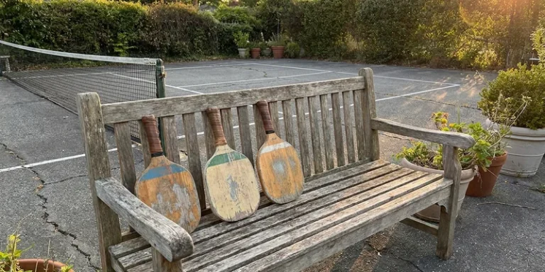 three vintage wooden paddles leaning against a garden bench